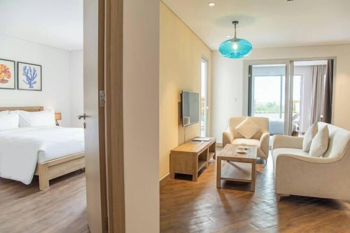 A hotel room with a bed, a TV, a wooden coffee table, a sofa, and a balcony with a view.