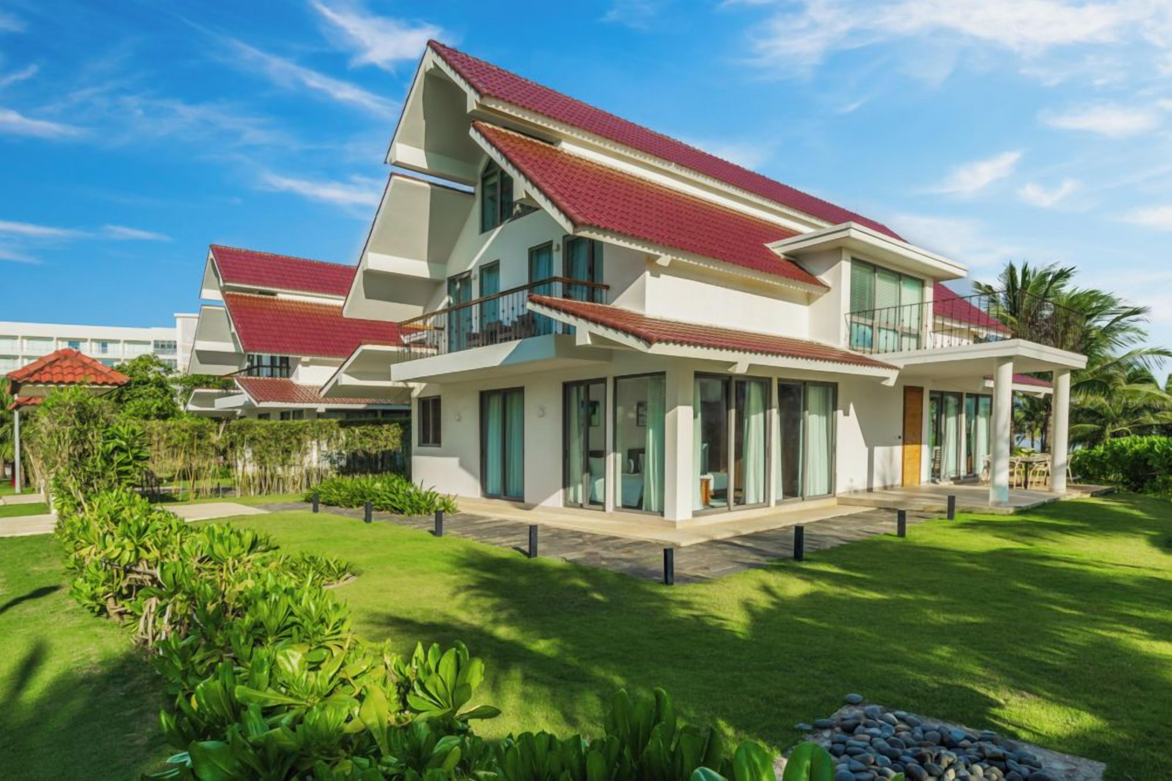 A modern two-story house with a red-tiled roof, large windows, and a well-maintained lawn.