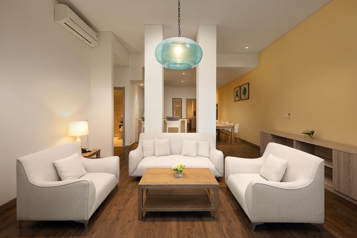A modern living room with a sofa set, a coffee table, and a hanging light fixture.