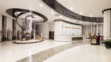 A modern hotel lobby with a central spiral staircase, a reception desk, and a clean, polished floor.