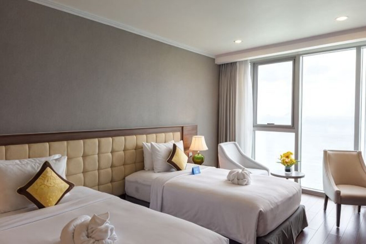 Une chambre d’hôtel avec deux lits, un coin salon et une grande fenêtre.