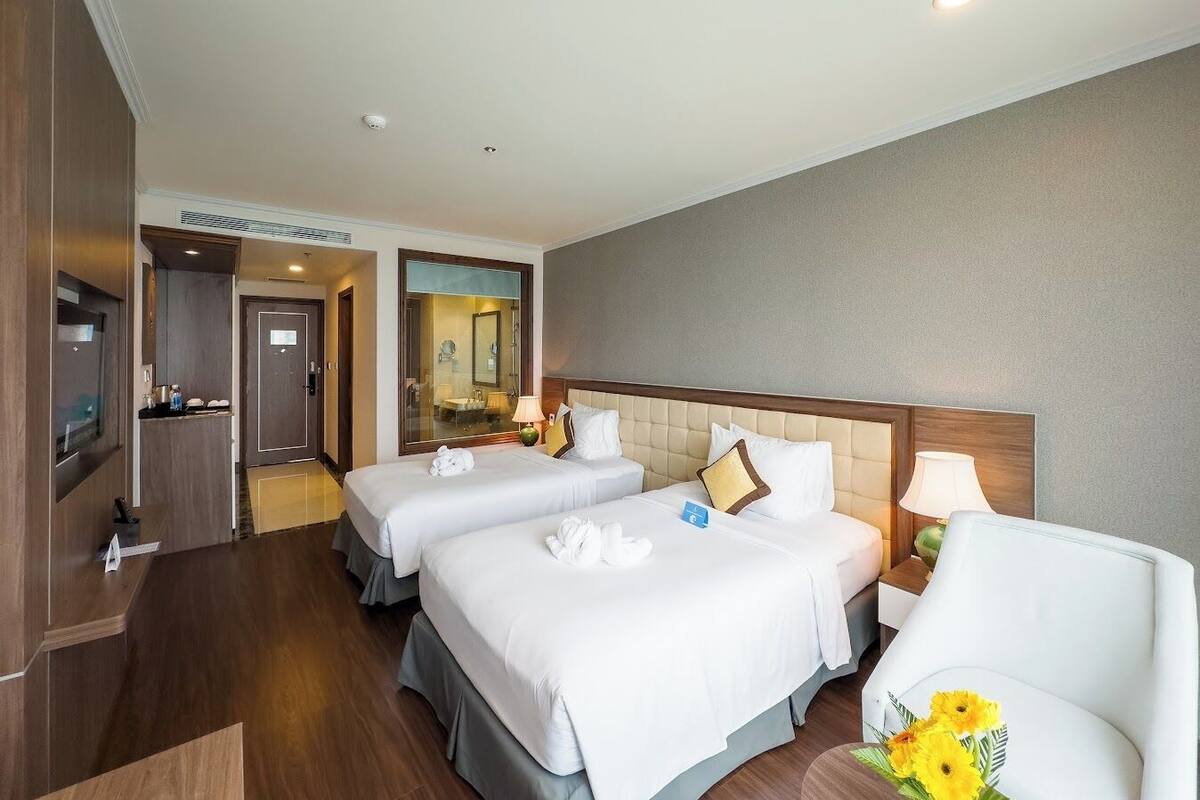 Een hotelkamer met twee bedden, een televisie, een bureau en een stoel.