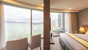 A hotel room with a large window, a bed, a chair, and a nightstand. - Nha Trang Horizon Hotel (Bac Nha Trang)