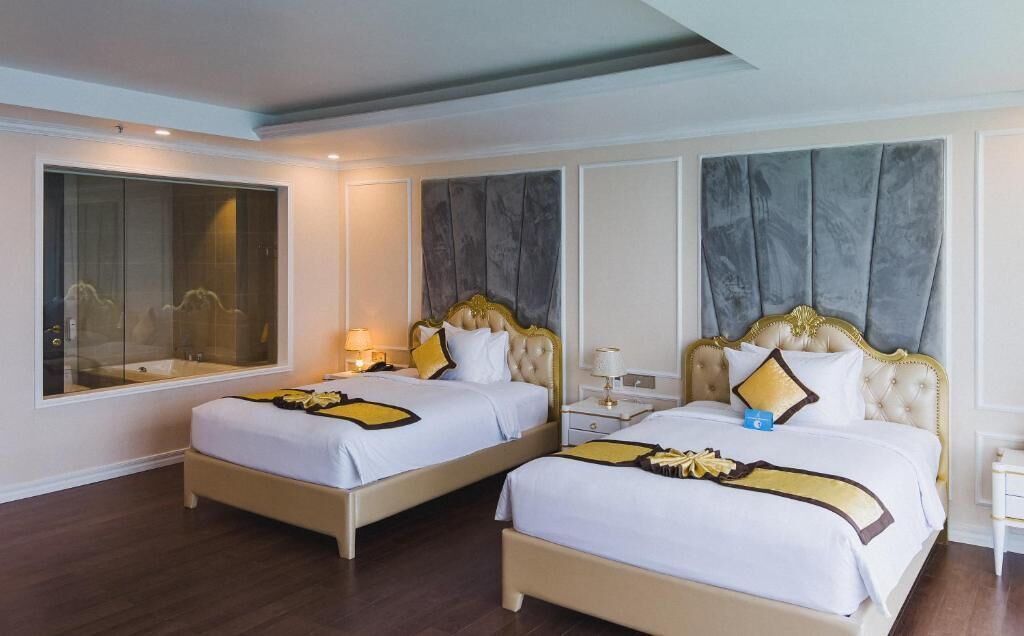 A hotel room with two beds, each with a headboard, bedside tables, and lamps.