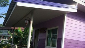 Ein zweistöckiges Haus mit violetten Außenwänden und einer Veranda.