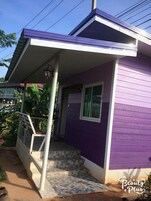 Una casa de dos pisos con fachada morada y un porche cubierto.