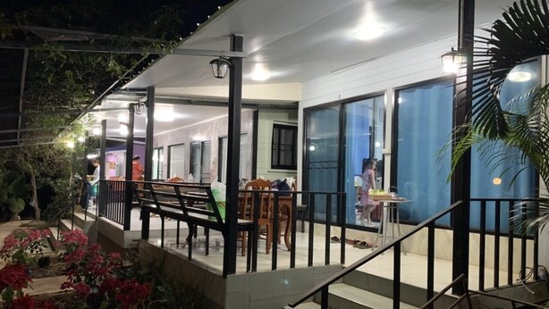 Ein Gebäude mit überdachter Terrasse, Stufen zu einem Balkon und einem Essbereich mit Tischen und Stühlen.