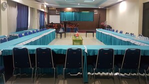 A conference room with a long table, chairs, a stage, and a whiteboard. - Hotel Darma Nusantara 2 (Makassar)
