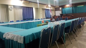A conference room with a long table, chairs, and a stage with a podium. - Hotel Darma Nusantara 2 (Makassar)
