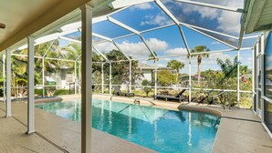 Piscina coberta com vista para palmeiras e casas.