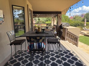 An outdoor patio with a table and chairs, a grill, and a view of the surrounding landscape.