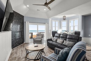 Relax in this stylish living area with a large sofa, armchair, and coffee table, offering a serene beach view.