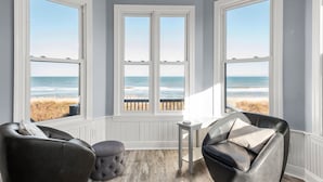 Une chambre avec vue sur la plage, aménagée de manière à créer un coin salon avec deux fauteuils en cuir et une petite table.