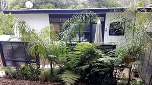 Una casa moderna con giardino recintato, un'antenna parabolica e diverse piante.