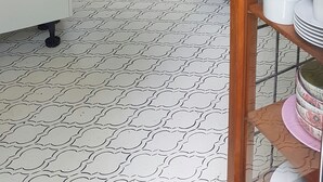 Una cucina compatta con mobili bianchi, un frigorifero, un tostapane e un lavello.