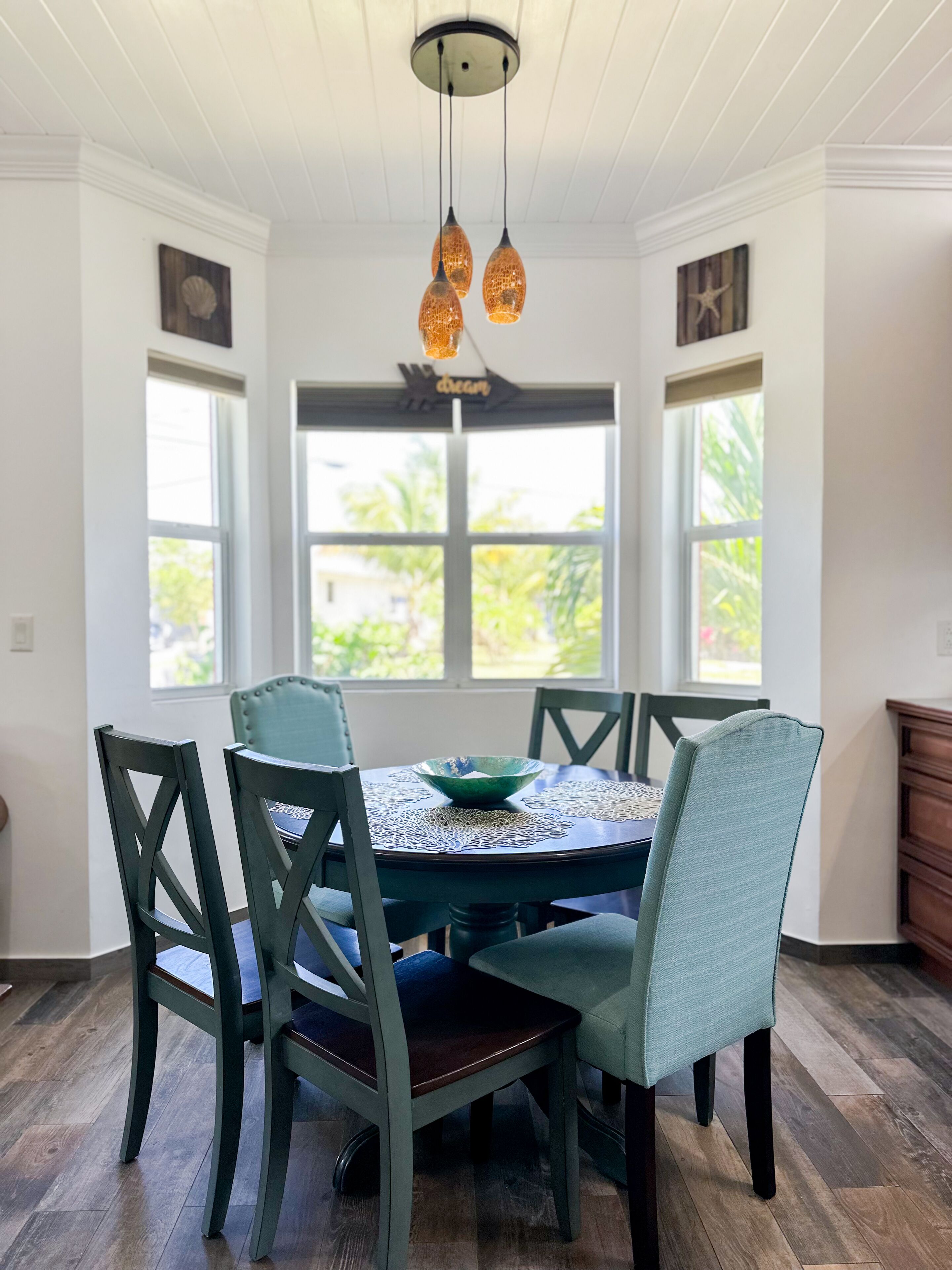 Un coin repas comprenant une table ronde, six chaises et un luminaire suspendu.
