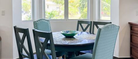 Un coin repas comprenant une table ronde, six chaises et un luminaire suspendu.
