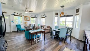 A spacious living area with a wooden ceiling, a dining table, and a kitchen area. - Paradise Found,GREAT LOCATION,free golfcart, dishwasher, sup, kayak, rain water  (Spanish Wells)