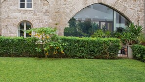 A stone building with a large arched window and a well-maintained hedge. - Luxury Gattopardo Loft - LAGO Design by Wonderful Italy (Palermo)