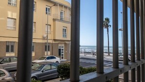 Blick auf ein Gebäude mit einem Balkon, der auf eine Straße mit geparkten Autos und einer Palme blickt.
