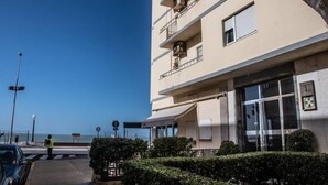 Ein mehrgeschossiges Gebäude mit Balkonen, blauem Himmel und Blick auf das Meer.
