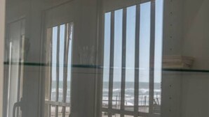 Ein Zimmer mit großen Fenstern und Blick auf den Strand, mit schlichtem, klarem Design.