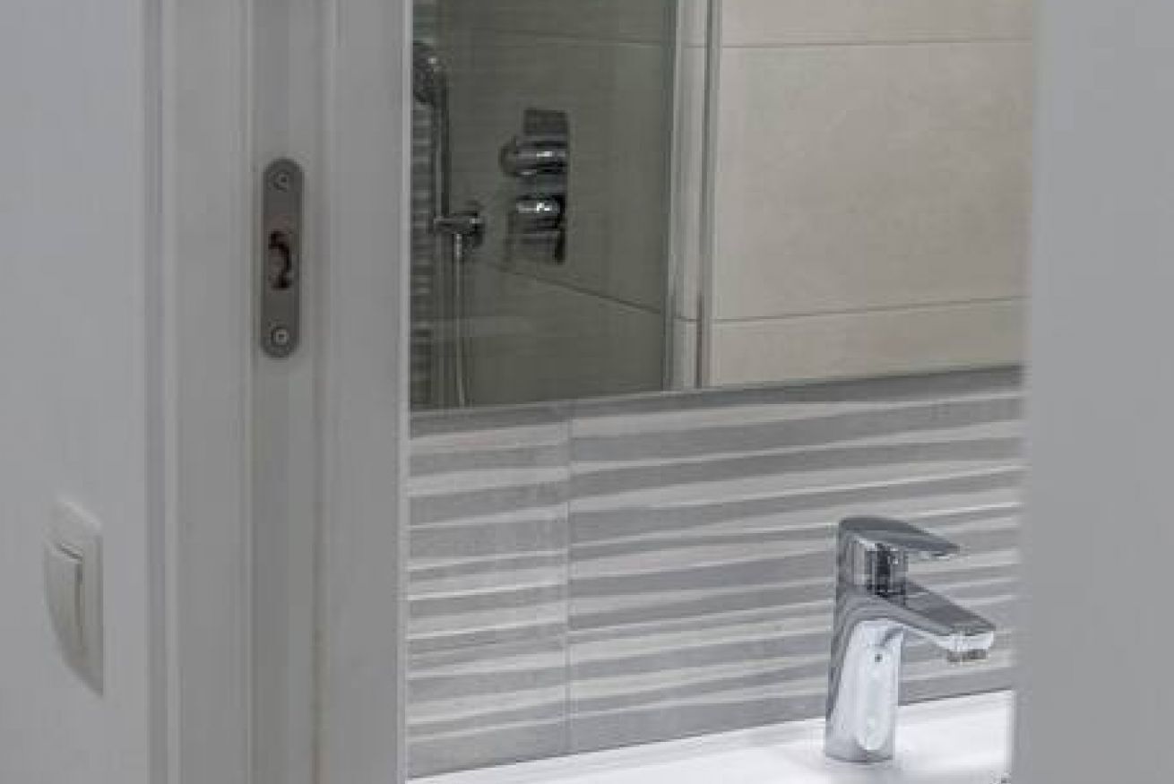 Un baño con ducha moderna, zona de ducha con paredes de vidrio y lavamanos con grifo cromado.