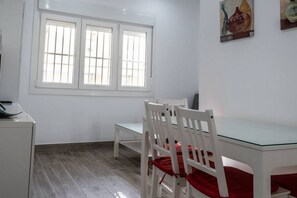 Una stanza piccola e pulita con una finestra, un tavolo bianco e due sedie bianche.