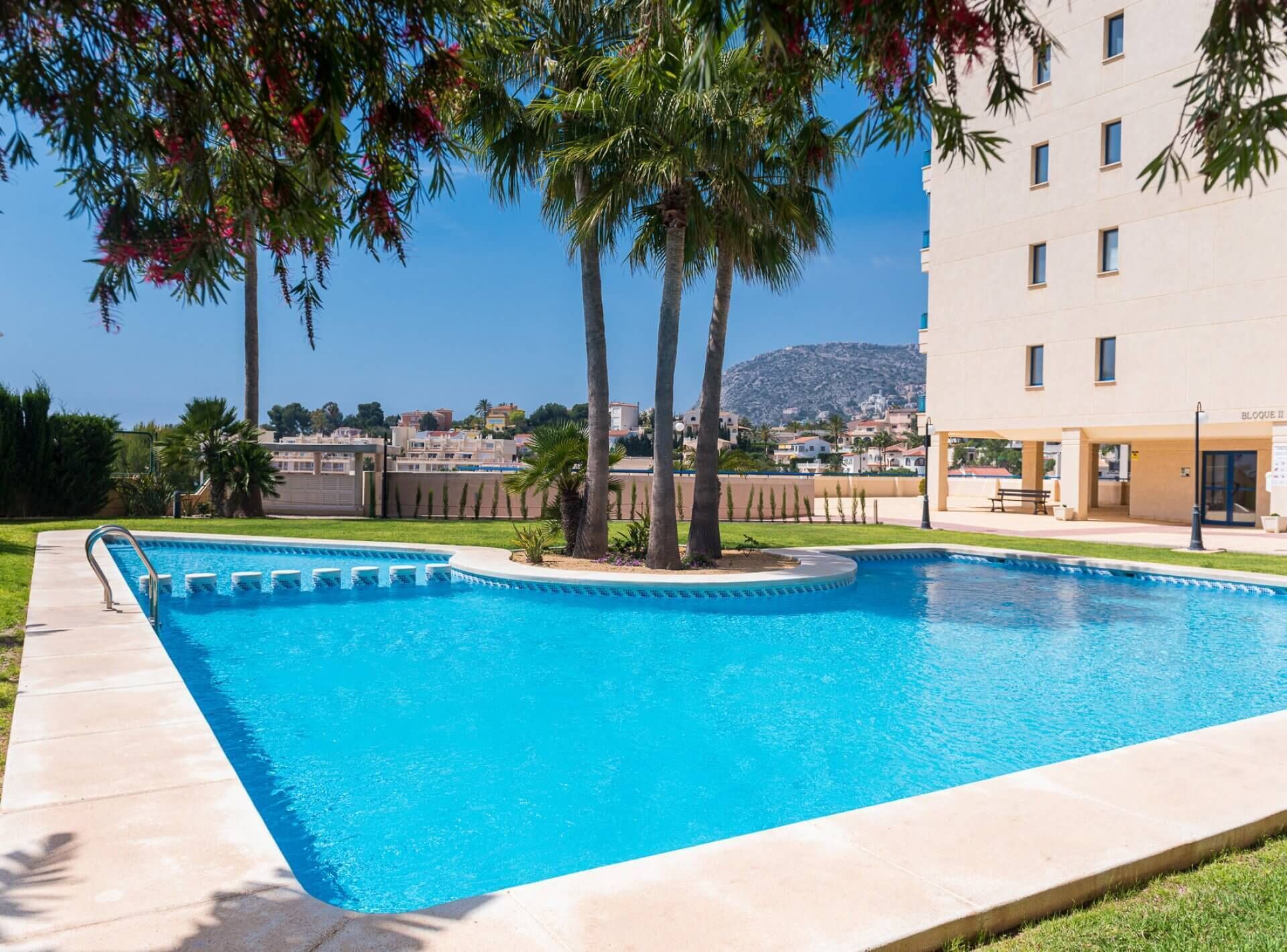 A swimming pool with a clear view of a building labeled "BLOQUE II" in the background.