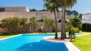 Una piscina con una parete in pietra e palme sullo sfondo.