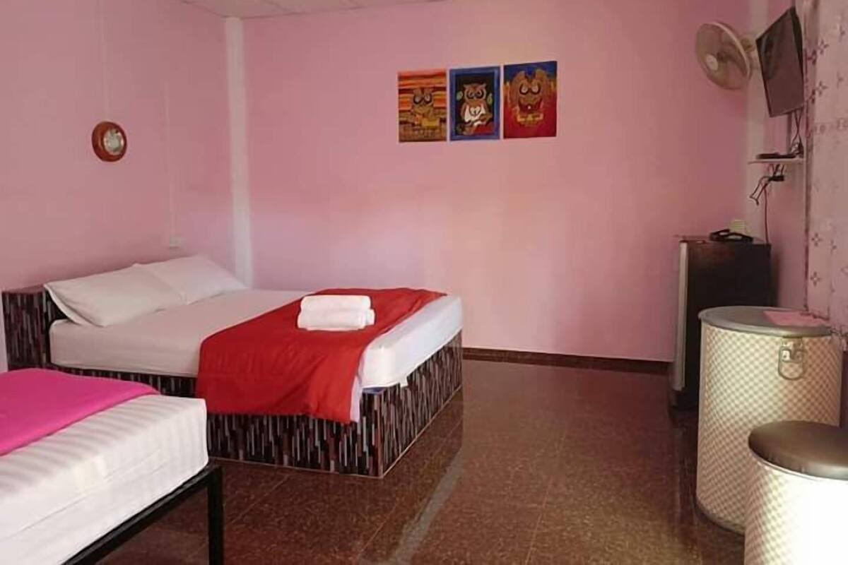 Una habitación con una cama, un escritorio pequeño, una silla y un televisor montado en la pared.
