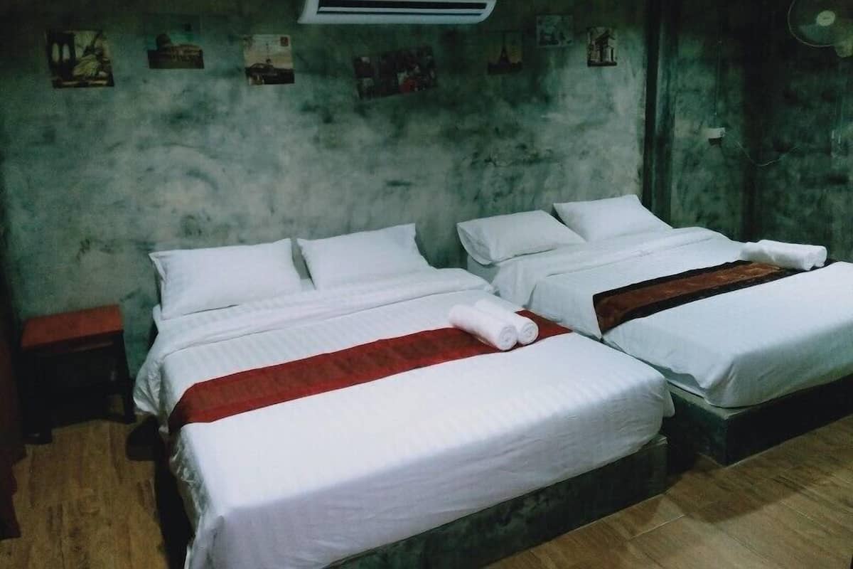 Una habitación con dos camas, aire acondicionado de pared y una pequeña mesa.