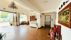 Eine Hotellobby mit einer Rezeption, einer Kandelaber, einem Kühlschrank und einem großen, gerahmten Kunstwerk an der Wand.