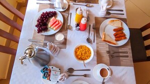 A breakfast table set with various dishes, including eggs, sausages, and a slice of pizza. - Calabash Hotel (Migori)