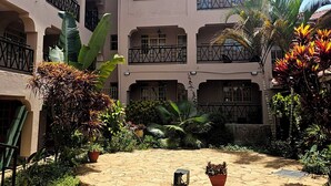 A multi-story building with balconies, a courtyard with potted plants, and a stone-paved area. - Calabash Hotel (Migori)