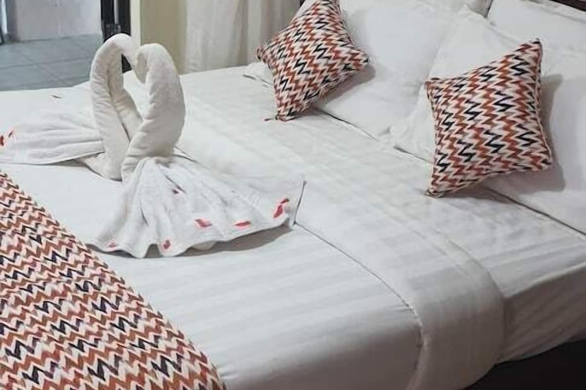 Ein Hotelzimmer mit Bett, Kissen, Decke und einer dekorativen Handtuch-Schwanen-Anordnung.