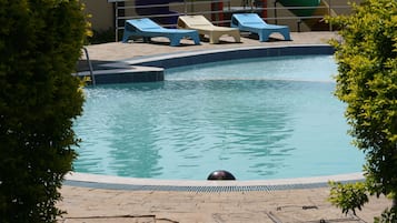 Una piscina al aire libre, sombrillas, sillones reclinables de piscina