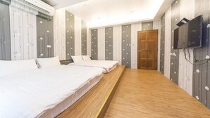 A hotel room with two beds, a wooden floor, a TV mounted on the wall, and a wooden door. - JU Meet up with ocean (Hengchun)