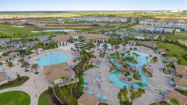 A resort with multiple swimming pools, lounge areas, and a golf course in the background. - ChampionsGate, 9 Bed Superb Luxury Villa, Sleeps 34, South Facing Pool/Spa. (ChampionsGate)