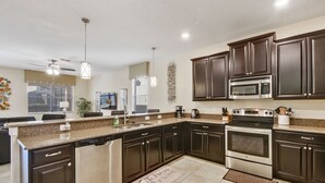 A modern kitchen with dark cabinets, stainless steel appliances, and a kitchen island. - ChampionsGate, 9 Bed Superb Luxury Villa, Sleeps 34, South Facing Pool/Spa. (ChampionsGate)
