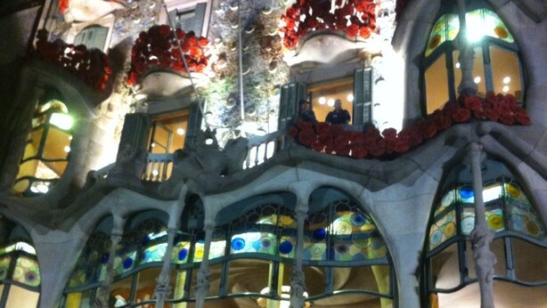 Un edificio con diversi balconi decorati con fiori rossi, ampie finestre a vetri colorati e un cartello con la scritta "CASA BATTÓ".