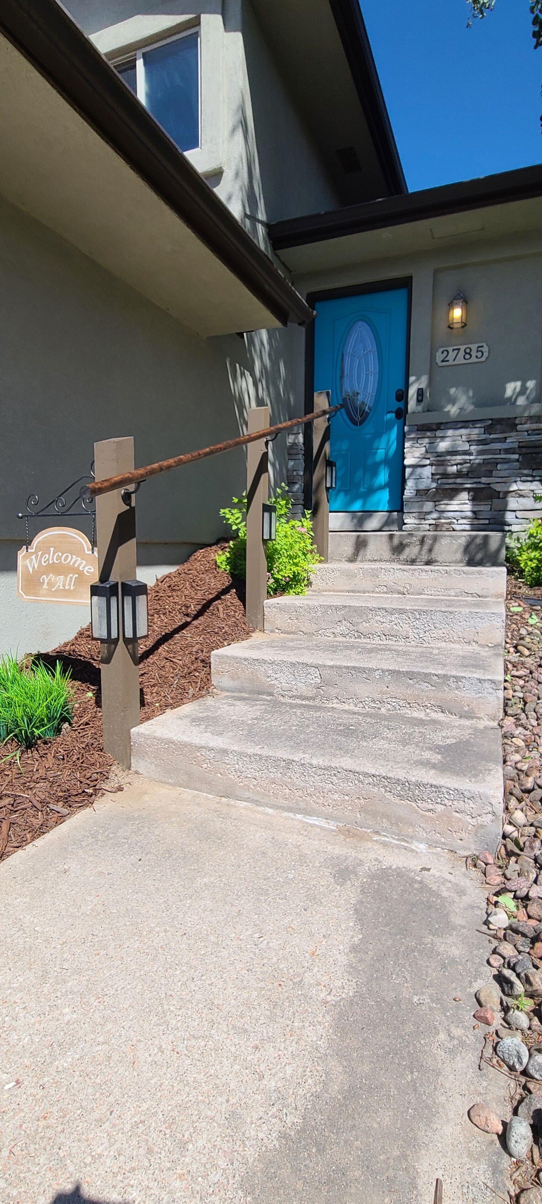 A concrete staircase leading to a blue door with a 'Welcome Y'all' sign.