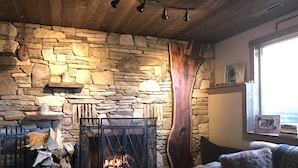 Una chimenea de piedra con fuego, techo de madera y pared de piedra.