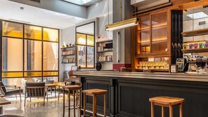 A modern bar area with wooden stools, a counter with a coffee machine, and bookshelves. - Albergo Etico Roma (Rome)
