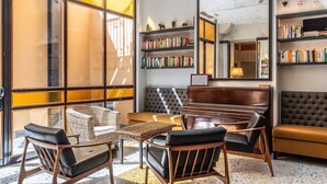 A cozy reading area with a sofa, chairs, and a small table. There are bookshelves with books and decorative items. - Albergo Etico Roma (Rome)