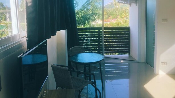 A modern room with a balcony, a small table, and a chair. - Sleep Inn (Koh Samui)