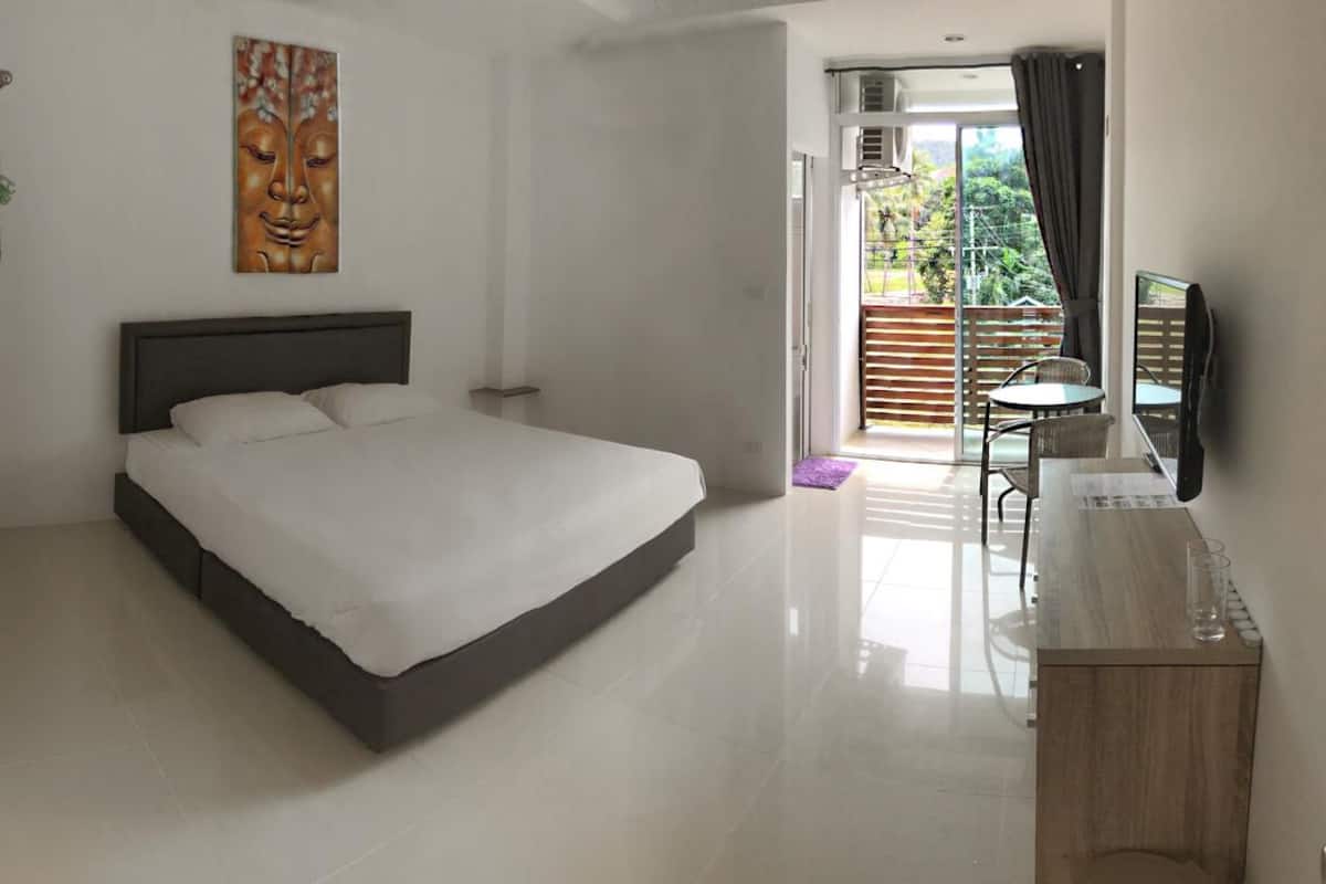 Un dormitorio con una cama grande, televisión y un balcón con vistas.