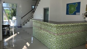 A modern interior with a tiled reception desk, a staircase, and a map on the wall. - Sleep Inn (Koh Samui)
