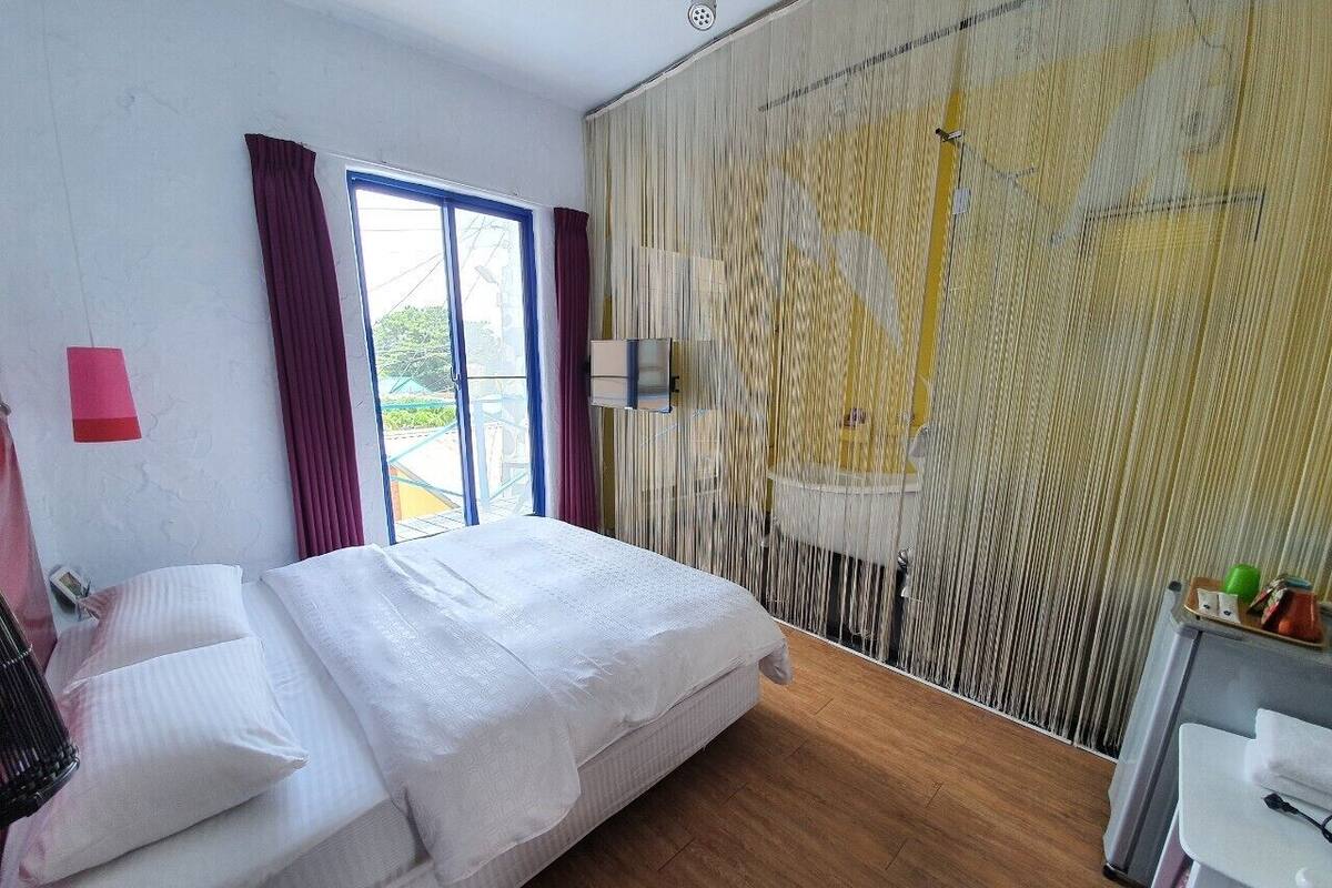 Un dormitorio con cama, escritorio y ventana con cortinas.