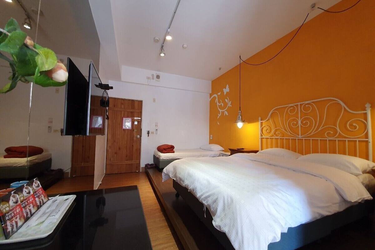 Una habitación de hotel con cama, escritorio, televisor y puerta.